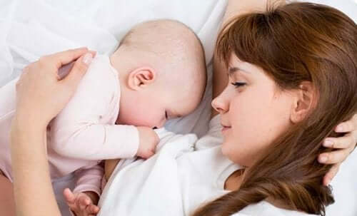 Mother and baby lying down in bed.