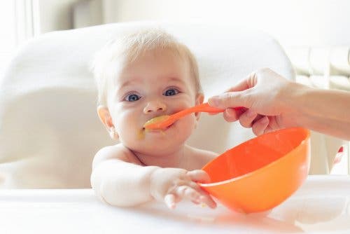 A baby eating mashed peas.