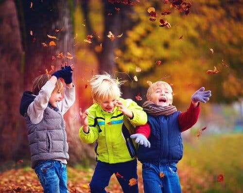 Three children throwing leaves.