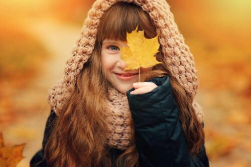 A girl holding a fall leaf.