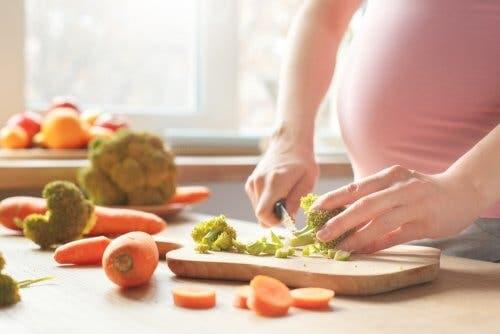 Gravid kvinde laver mad og følger fødevaresikkerhed under graviditet