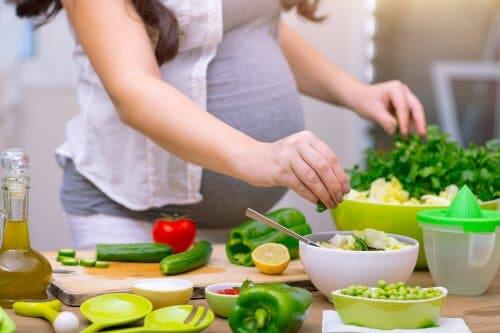 A pregnant woman making a salad.