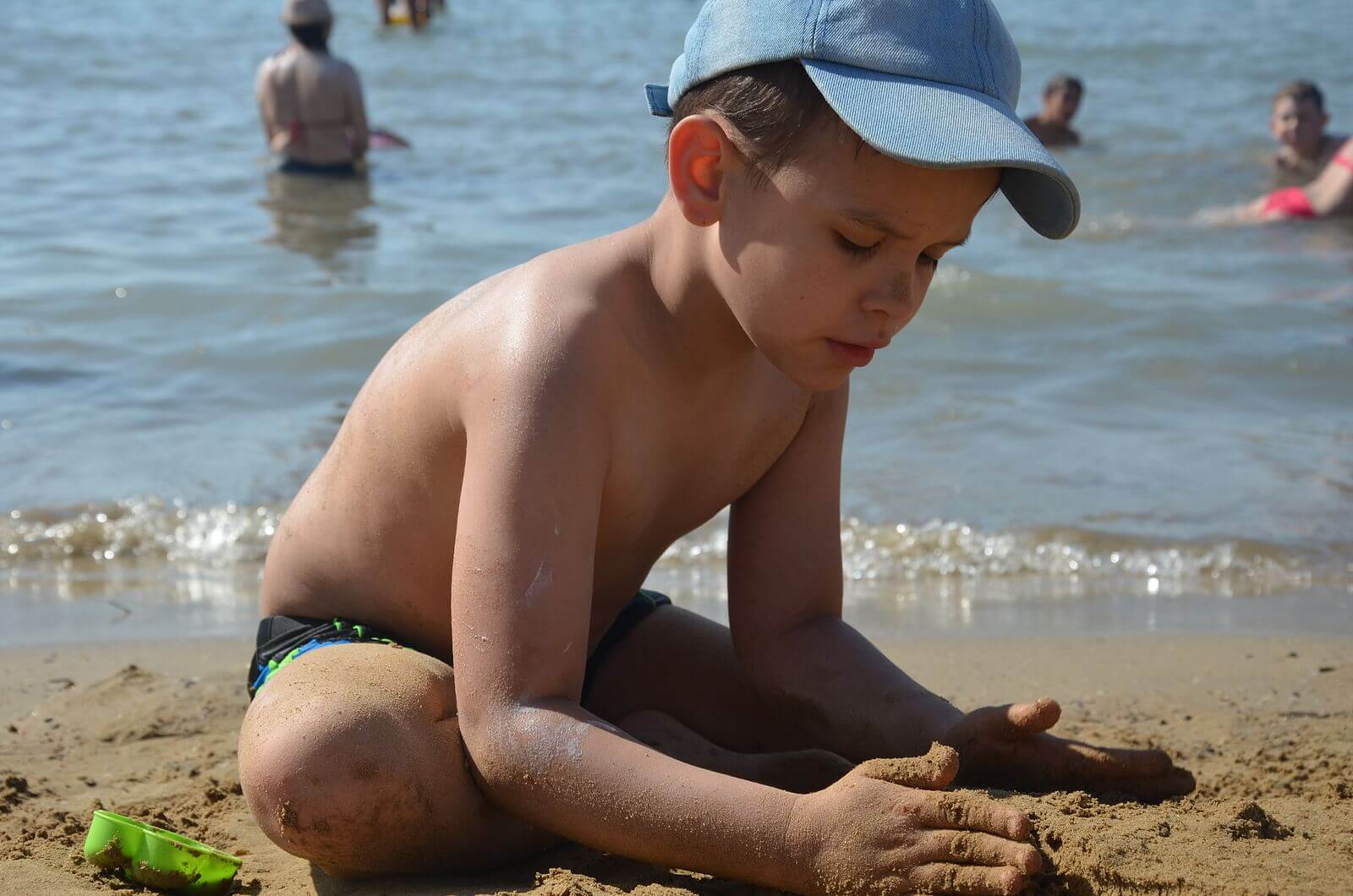 A child playing in the sand at the beach.