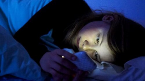 A girl on her phone in bed.