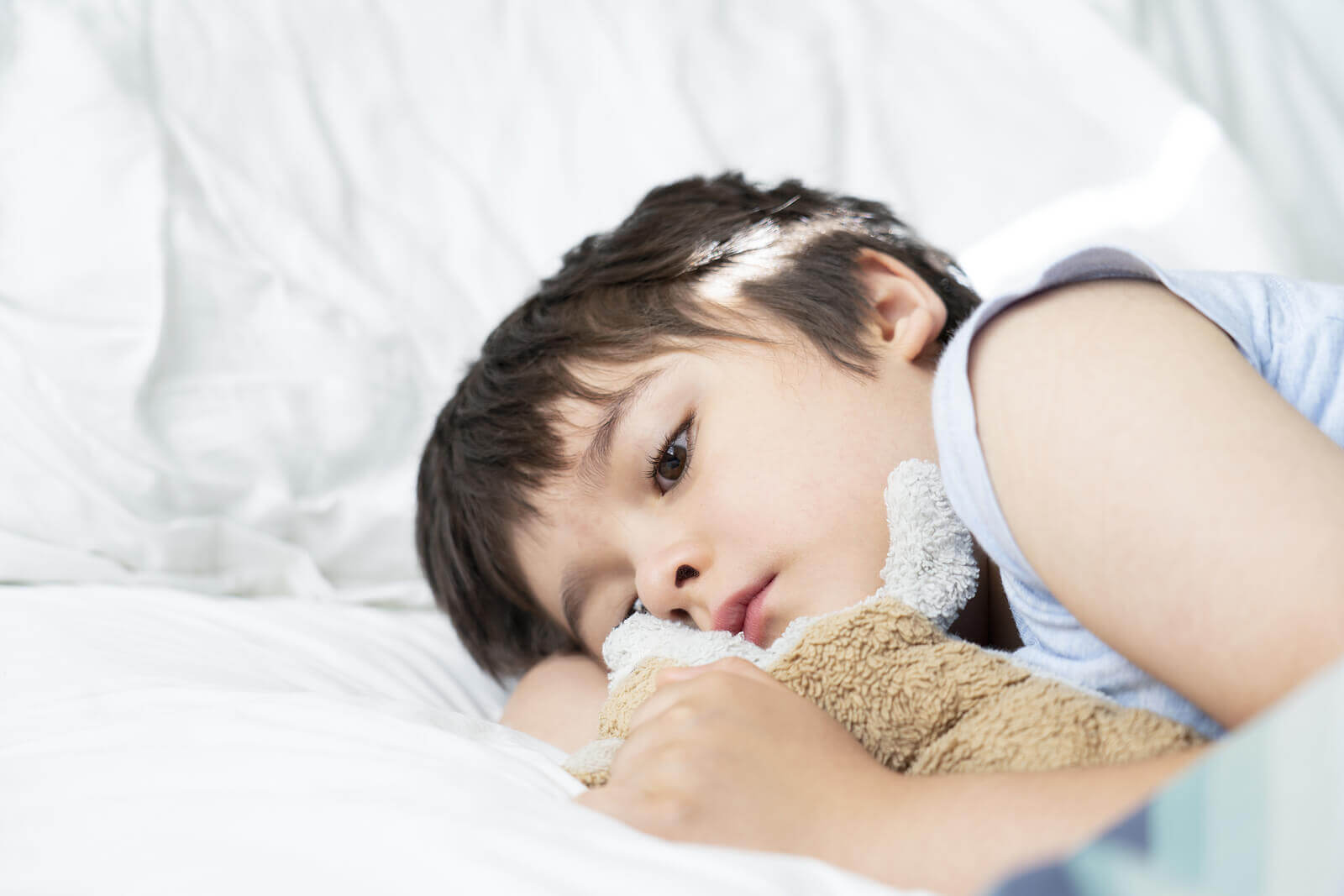 A sad child lying in bed.