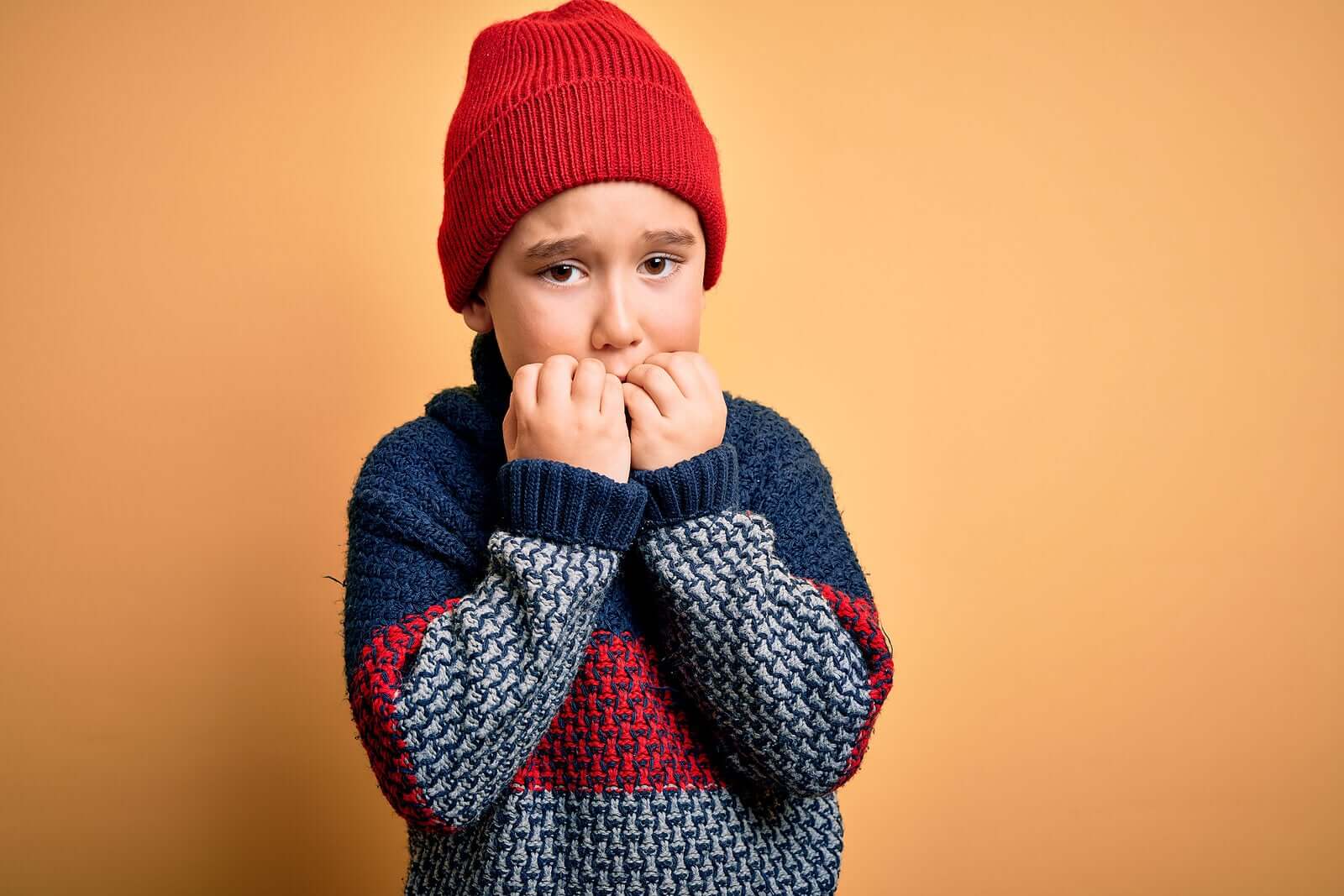 A frightened child biting his nails.