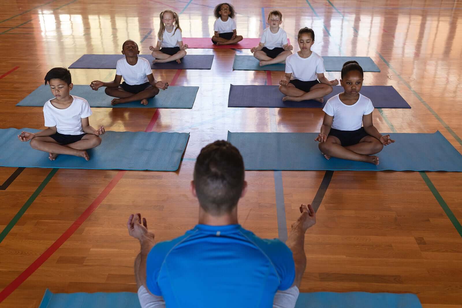 Children practicing yoga in a school gym.