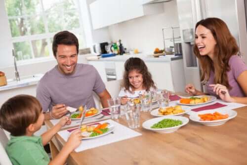 A family sitting down at the kitchen table eating a healthy meal and laughing together.