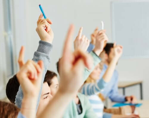 Elementary students raising their hands.