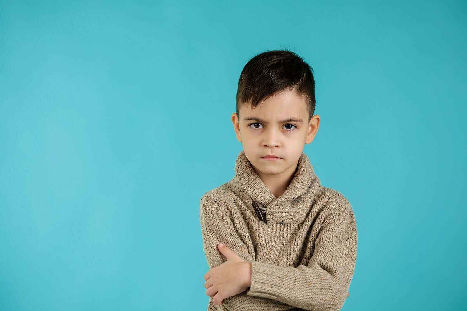 A small child crossing his arms and looking angry.