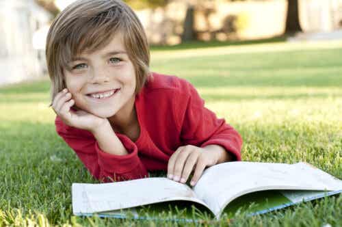 Child reading a book lying on the grass.