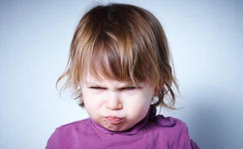 A two-year-old girl making an angry face.