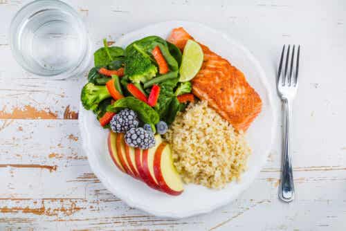 Salmon, rice, fruit, and vegetables on a plate.