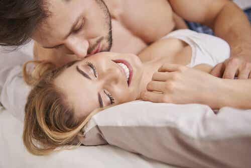 A man kissing his wife in bed.