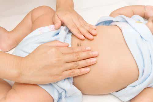 A mother touching her baby's belly with her finger tips.