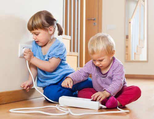 Toddlers playing with a power cord.