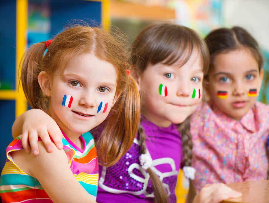Tre små flickor med olika flaggor målade på kinderna.