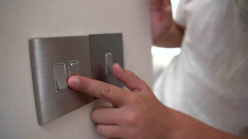 A small child playing with light switches.
