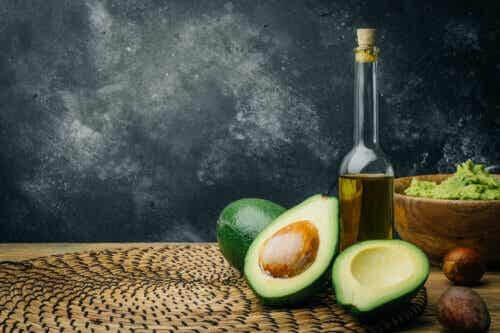 Bottle of olive oil and an avocado: sources of healthy fats.