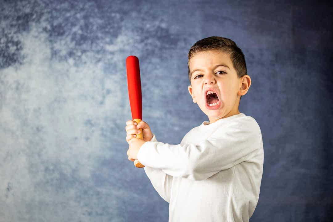 An angry child swinging a baseball bat.