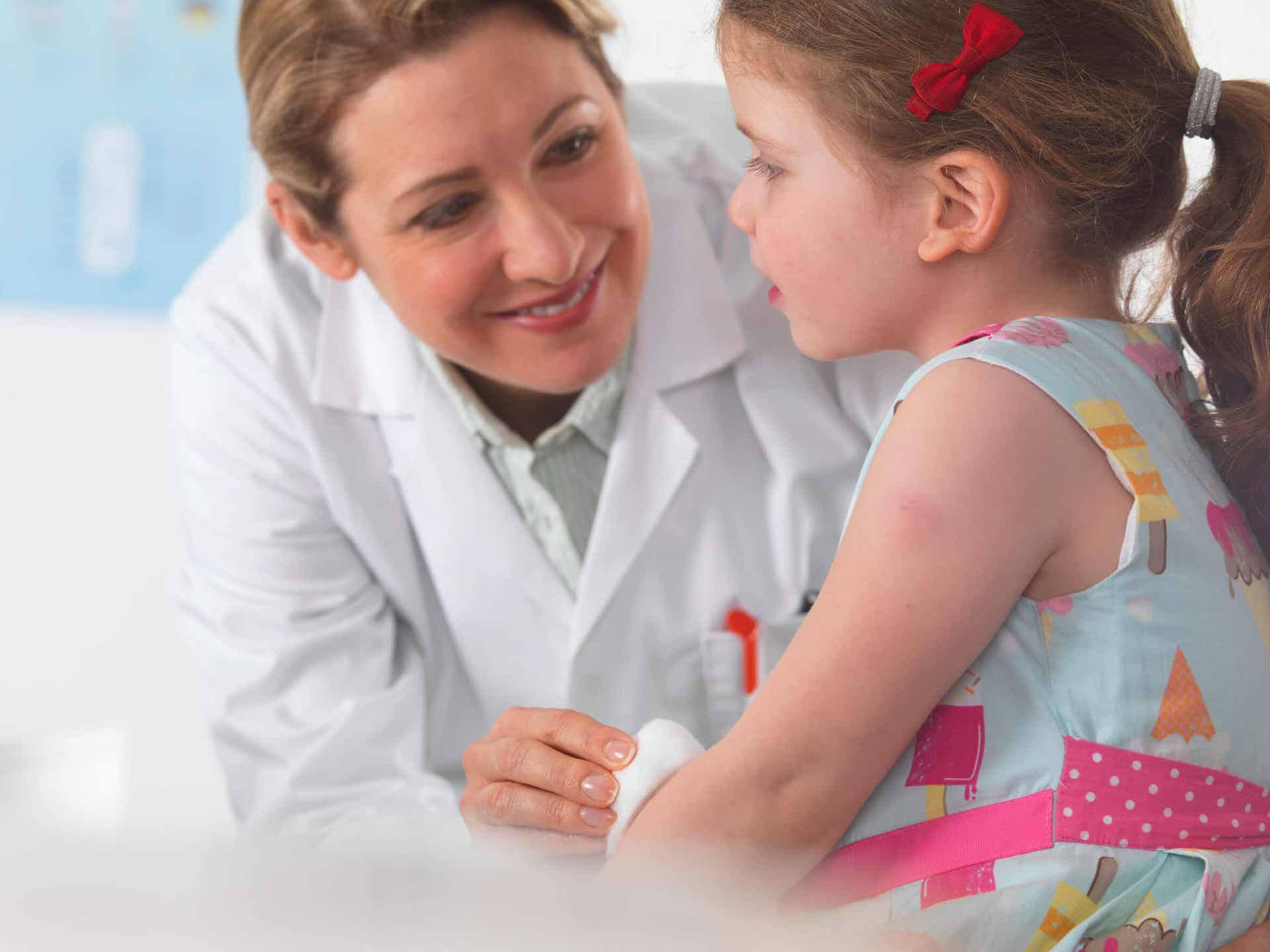 A doctor rubbing alcohol on a child's inner arm with cotton.