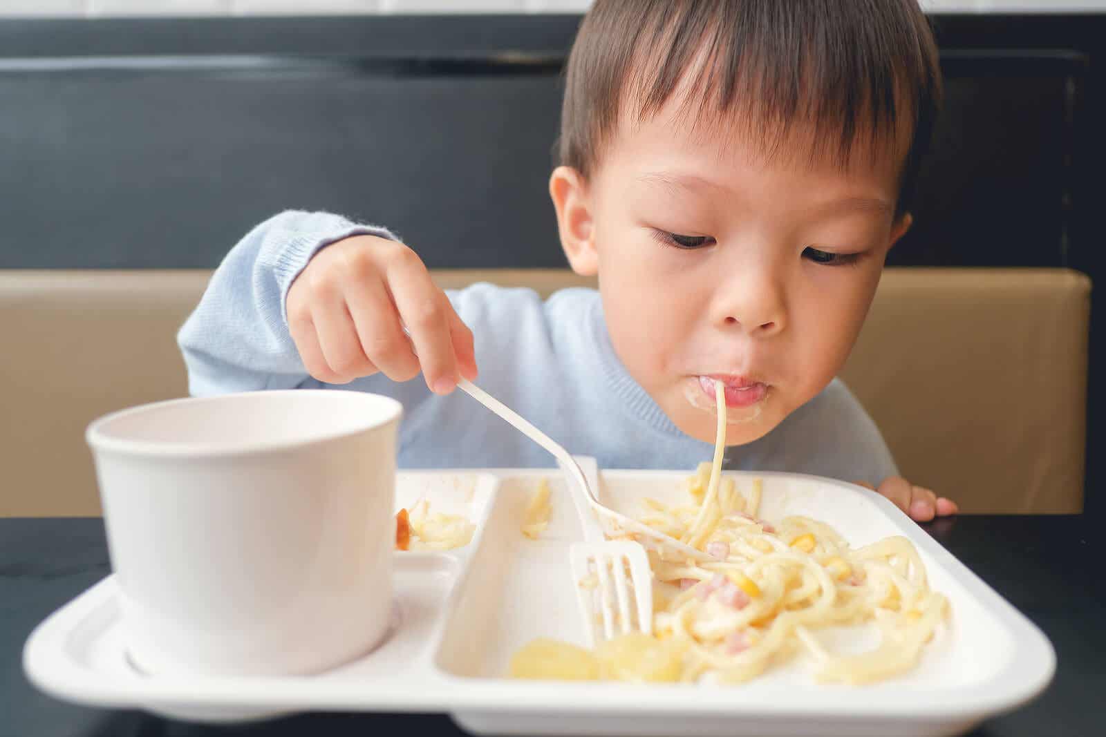A small child eating pasta.