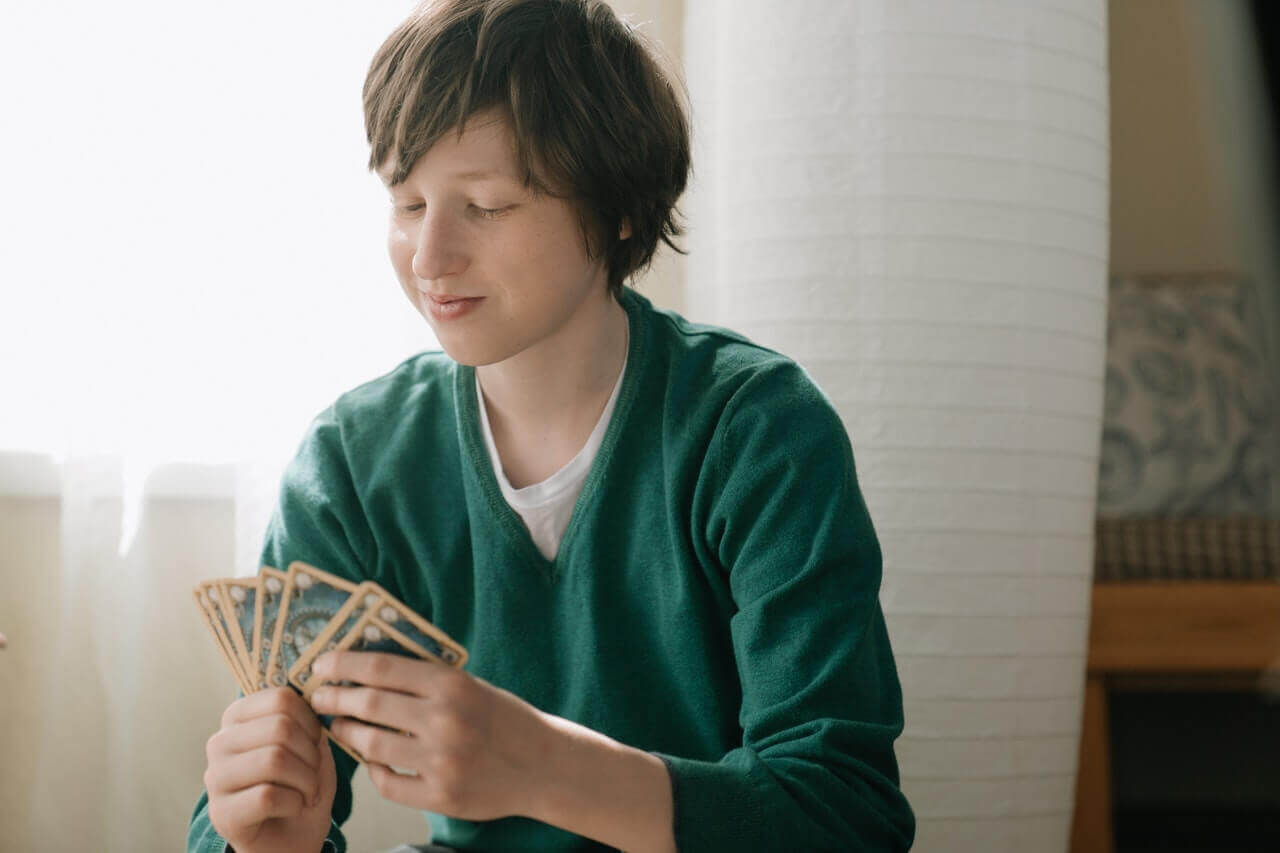 A teen holding a hand of cards.