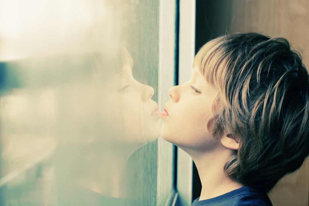 A child resting his chin on a window and looking outside.