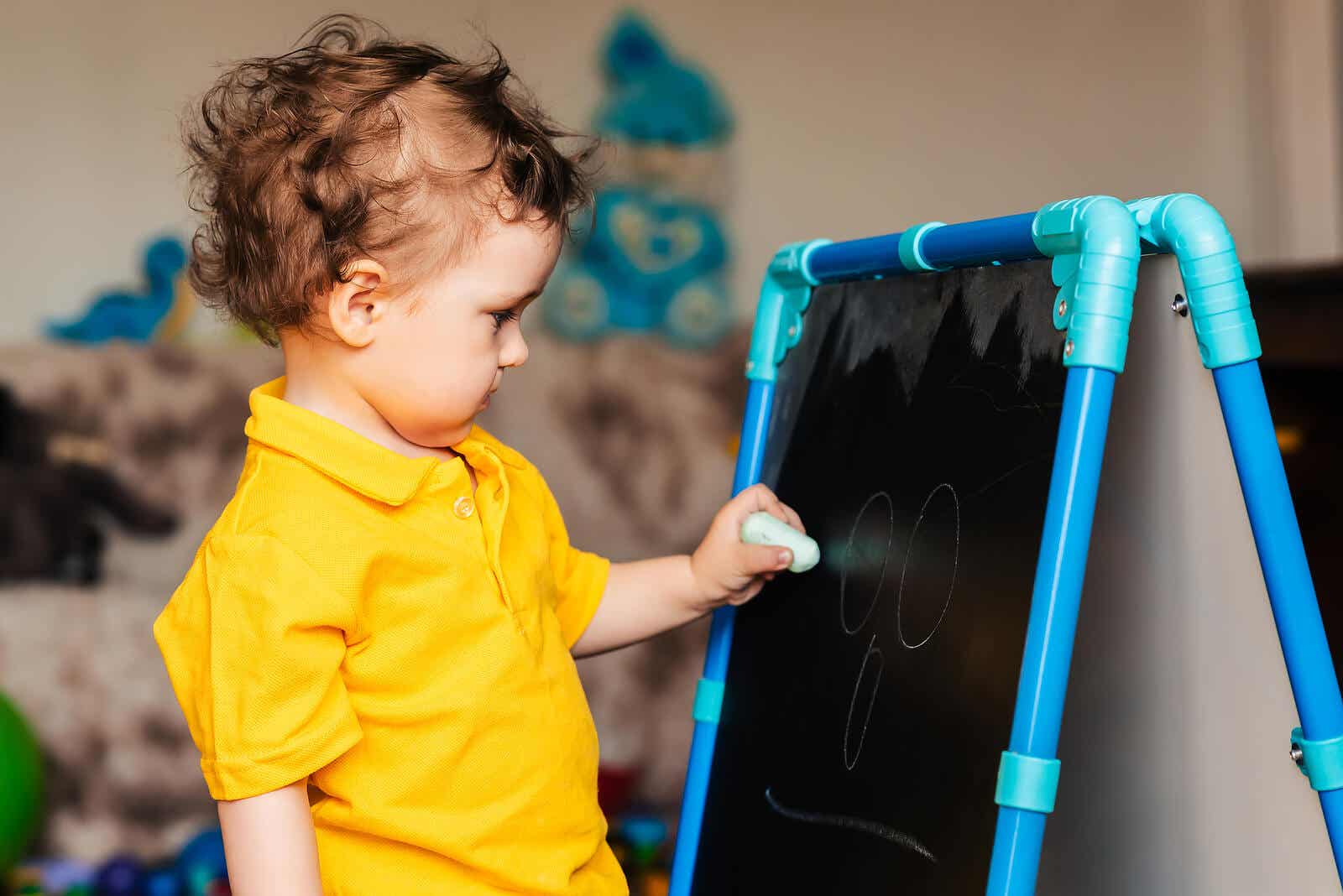 A toddler drawing on a chalkboard easel.