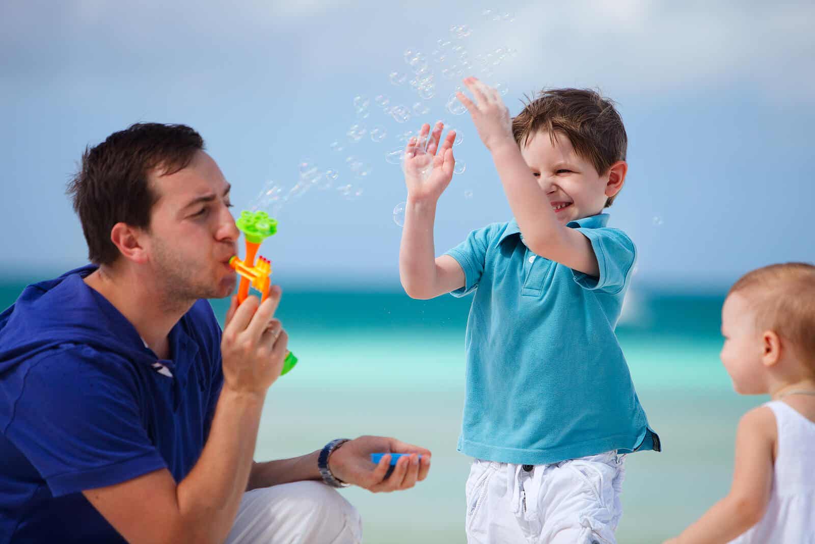 Een vader die met zijn kleine kinderen bellen blaast op het strand.