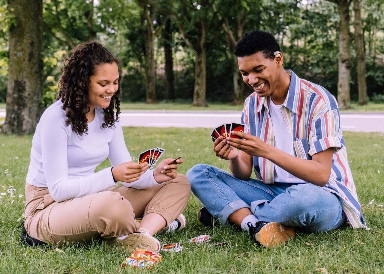 Para grająca w karty na trawie.