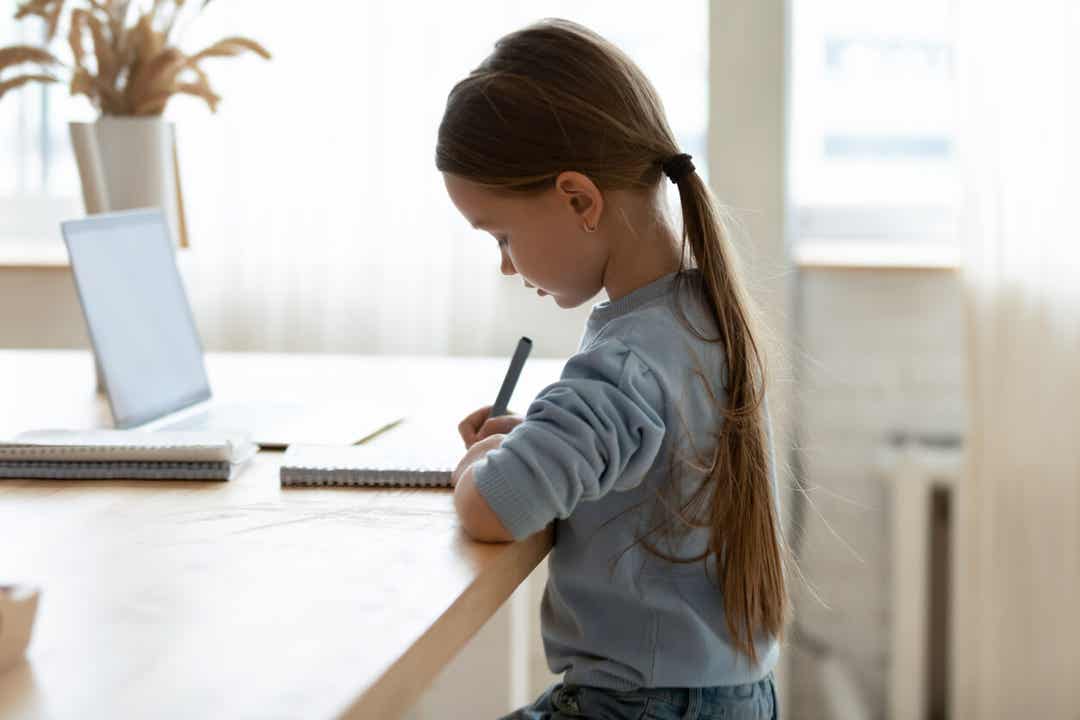 A child sitting at a table with her back straight.