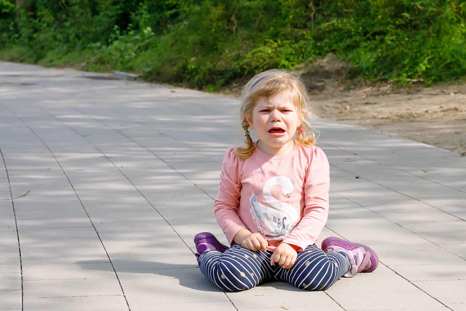 A toddler girl having a tantrum on the sidewalk.