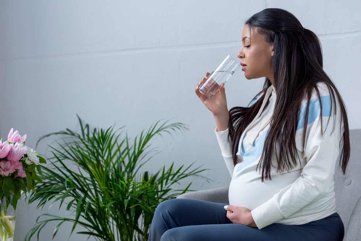 A black pregnant woman drinking water.