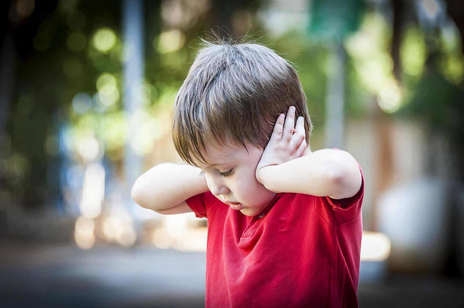 A toddler covering his ears.