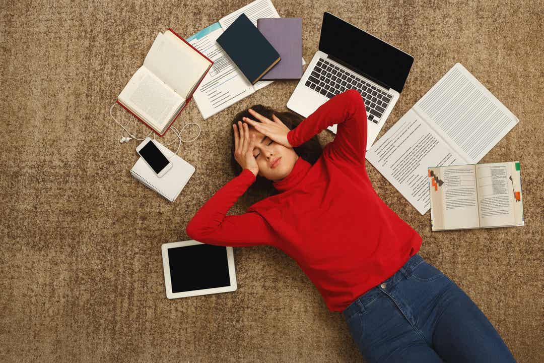 A young person lying on the floor feeling overwhelmed about school work.