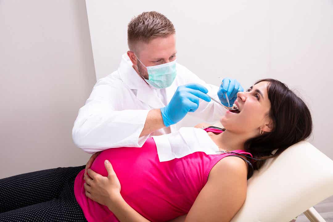 A dentist checking a pregnant woman's teeth.