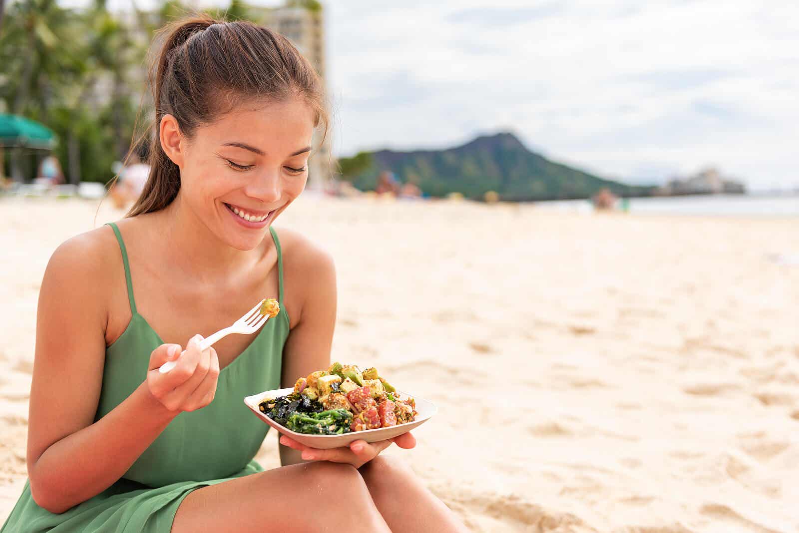 Vrouw die op het strand gezond voedsel eet dat thuis wordt bereid om voedselvergiftiging te voorkomen.