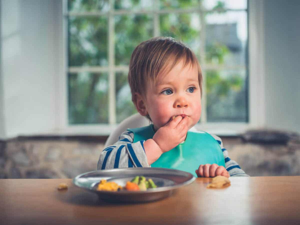 A baby eating with his hands.