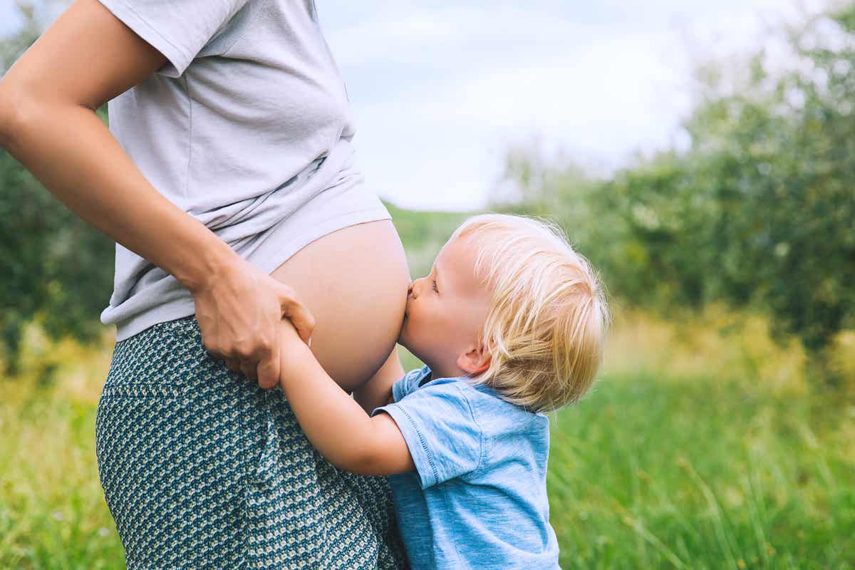 A boy kissing his mother's belly.