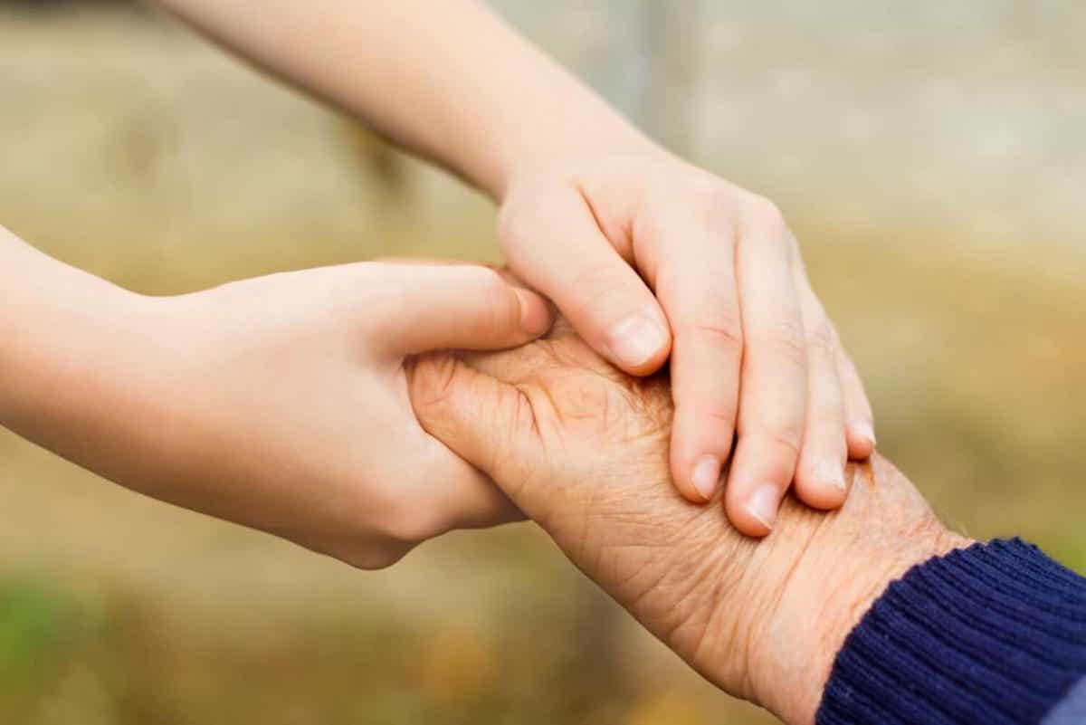 Een kind hand in hand met een bejaarde.