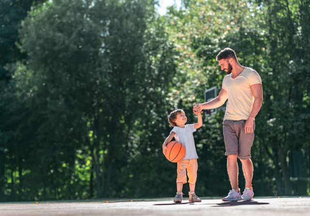 A dad playing basketball with his child.
