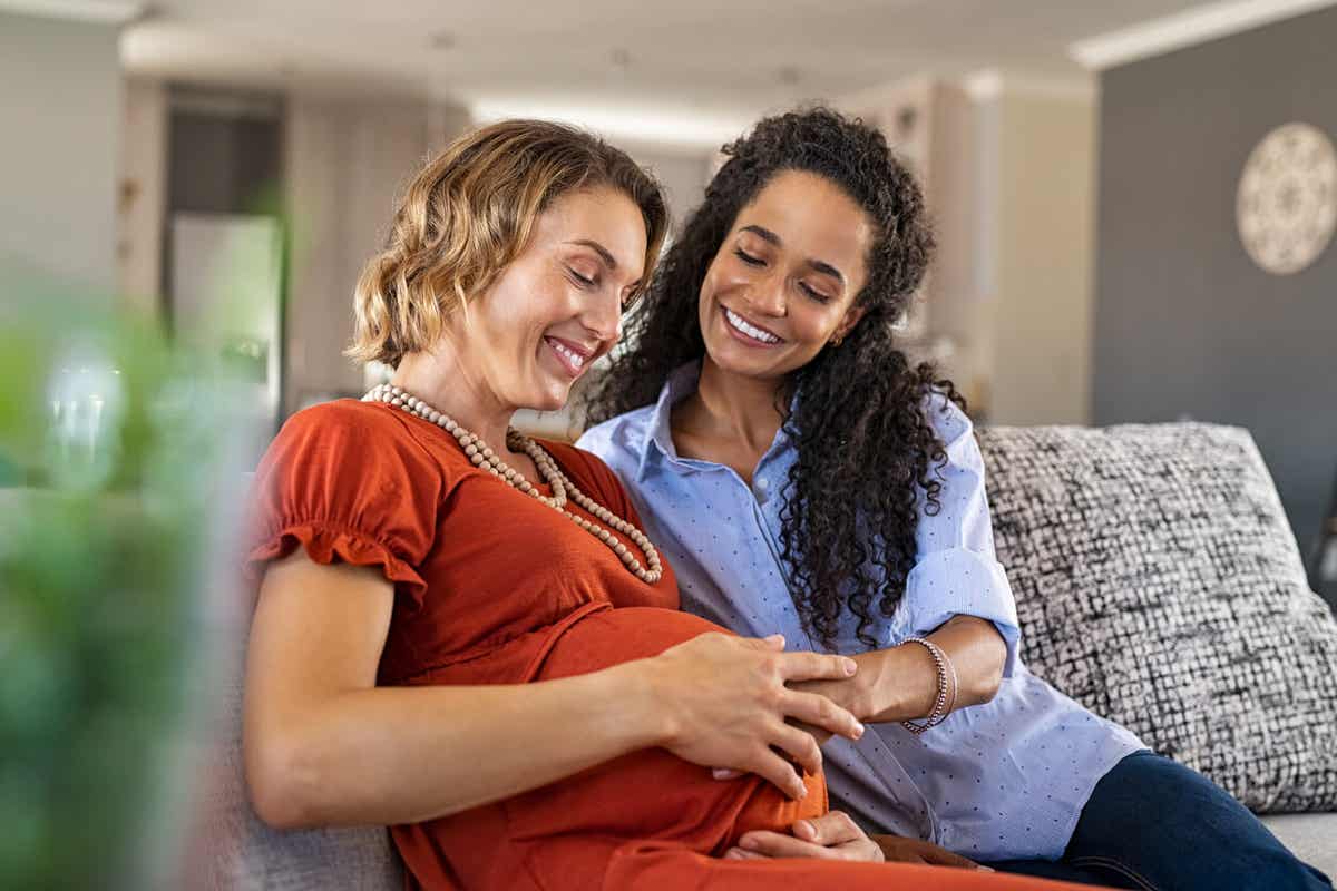 A woman smiling with her pregnant friend.