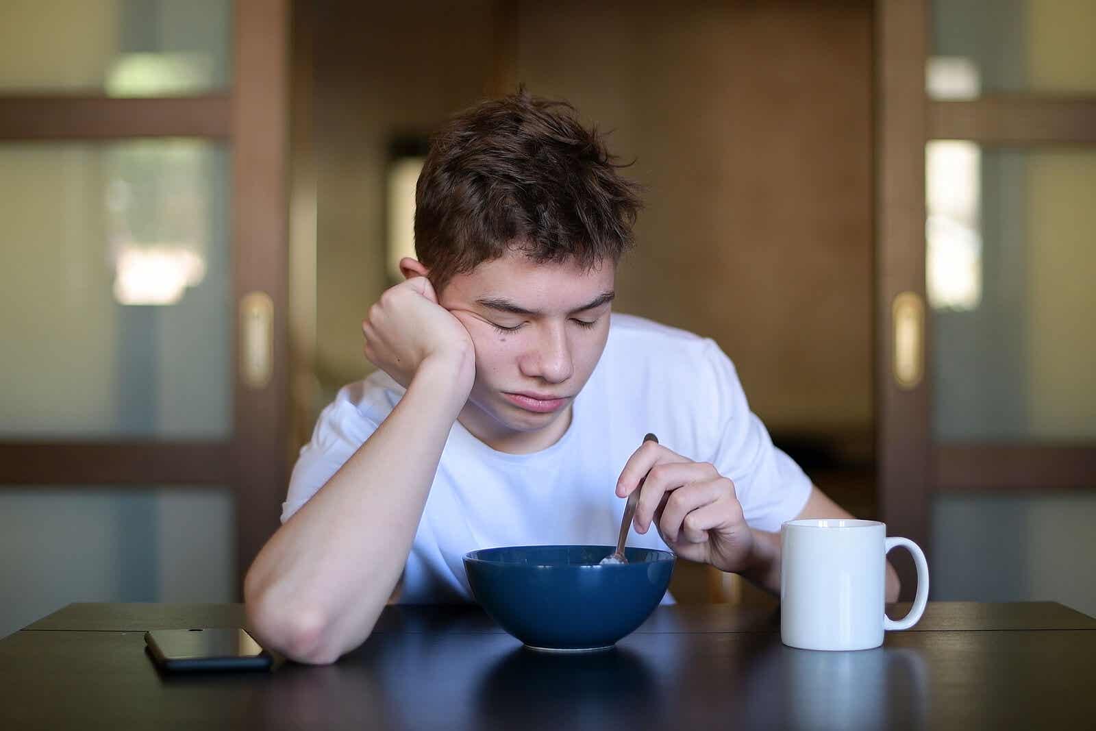 En teenager, der er træt ved morgenmaden