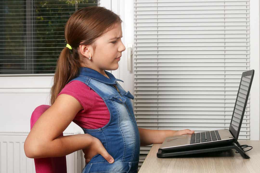 A young girl sitting at a computer desk with back pain.