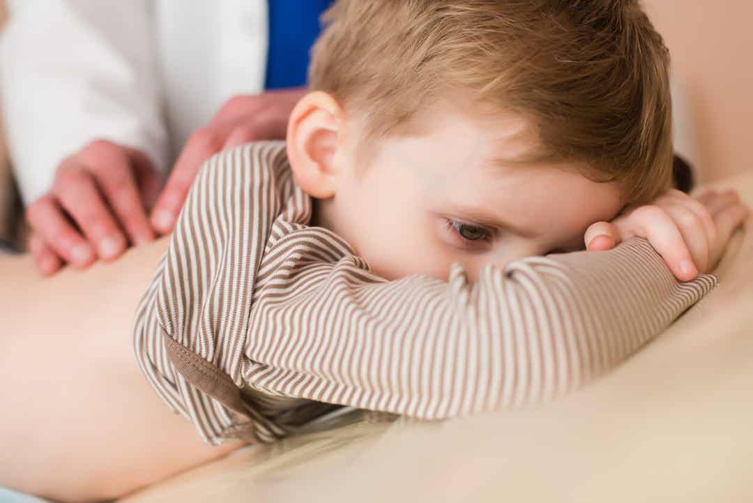 A doctor examining a young boy's back.