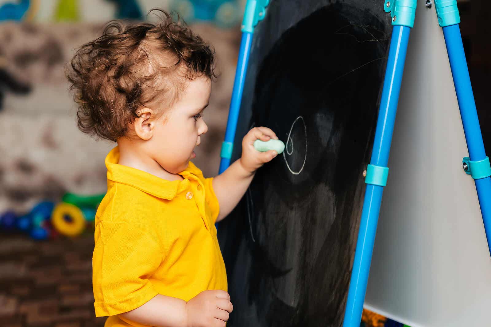 A toddler scribbling on a chalkboard.