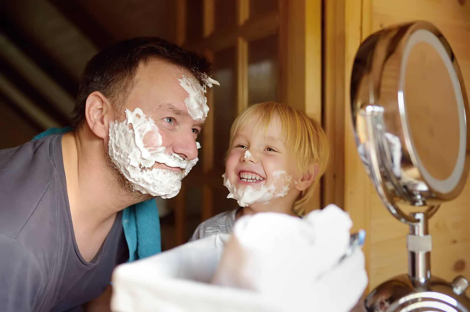 A father and son with shaving cream on their faces, smiling.