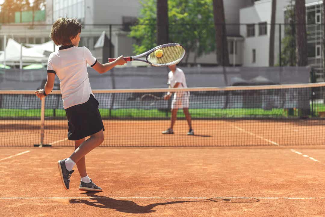 A child playing tennis with an adult.