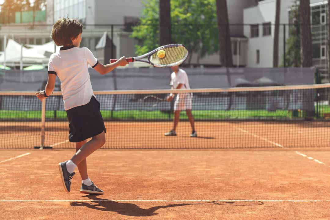 Et barn spiller tennis med en voksen